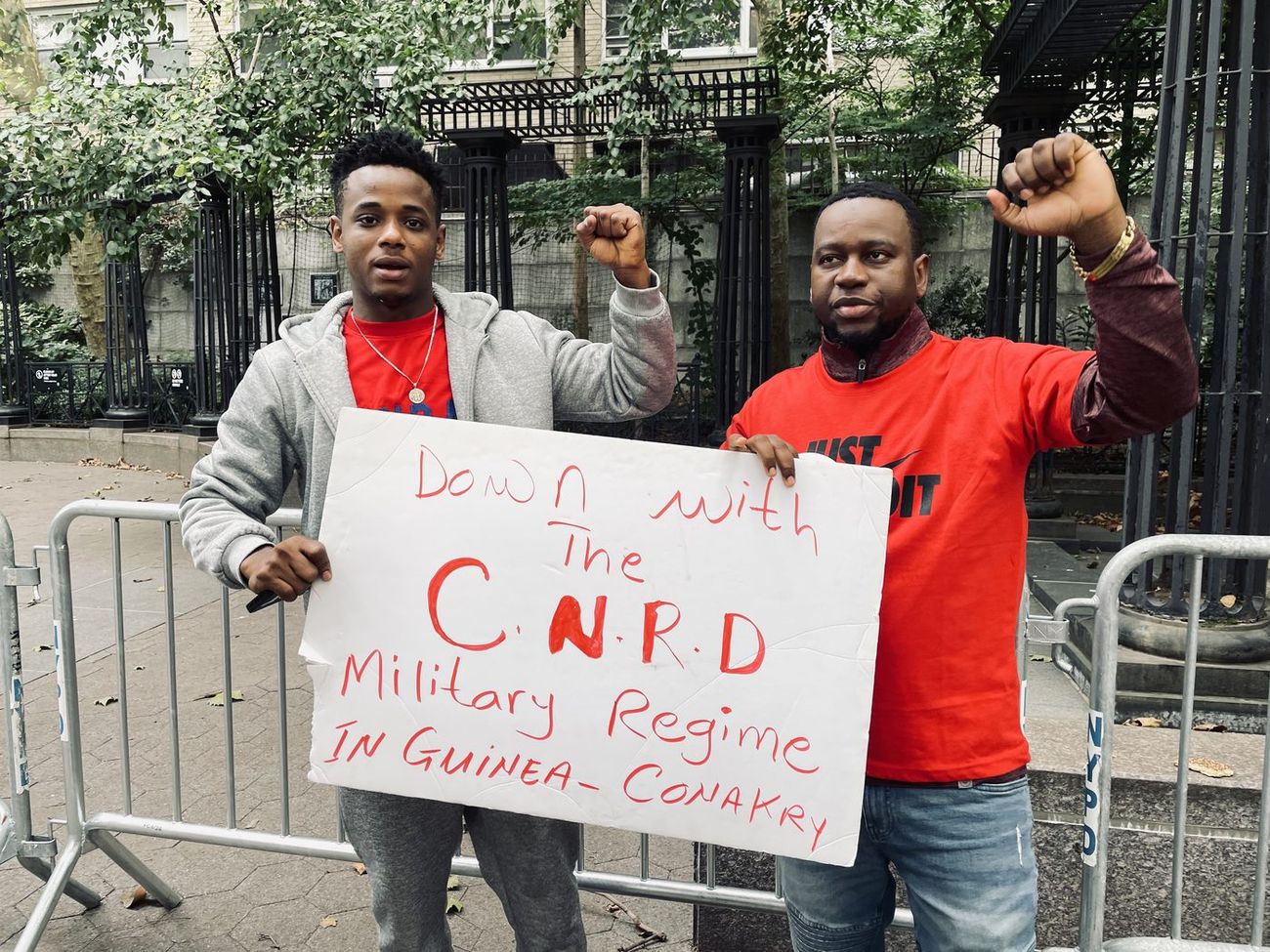 Two protesters holding a sign reading Down with the CNRD Military Regime in Guinea-Conakry