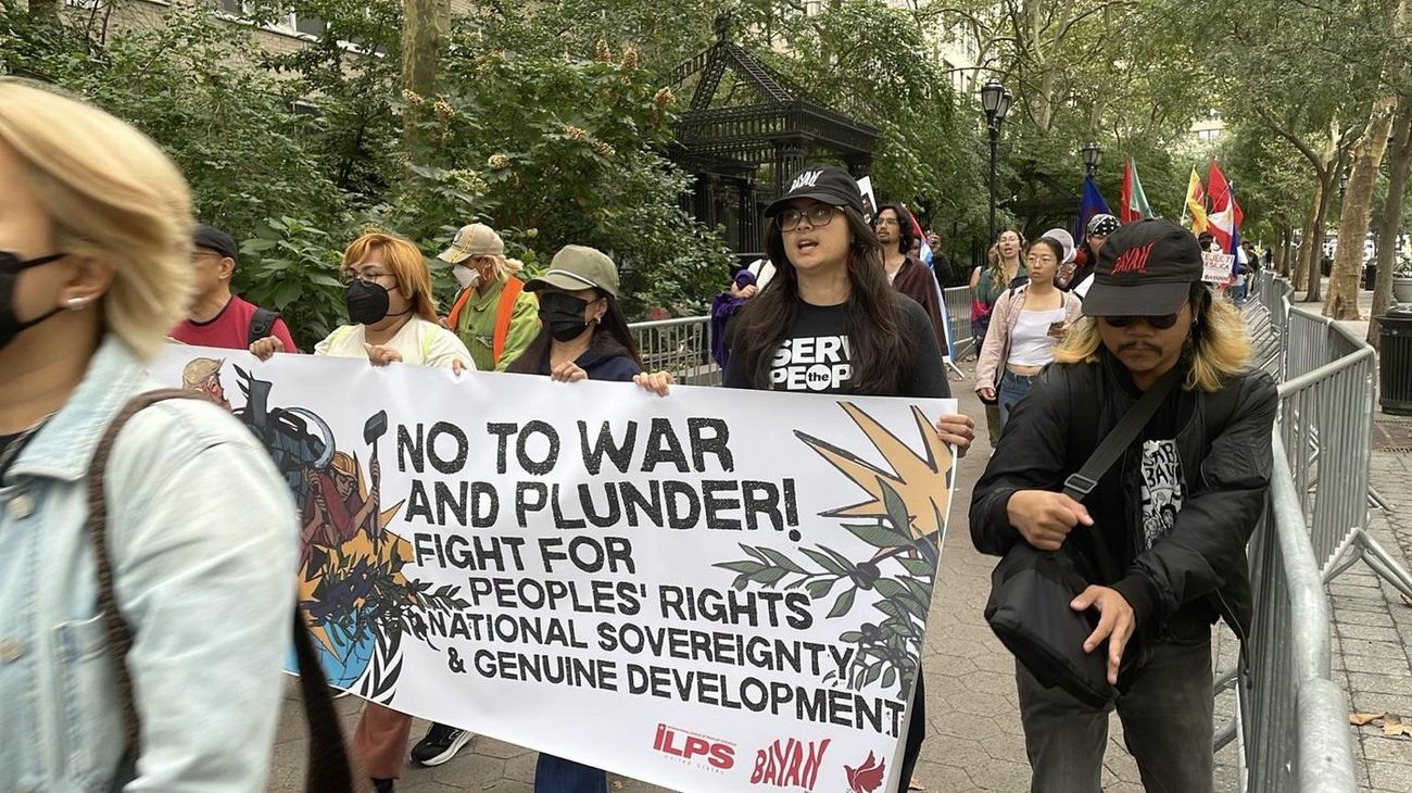 Marchers holding a banner reading No to War and Plunder, Fight for Peoples Rights, National Sovereignty and Genuine Development